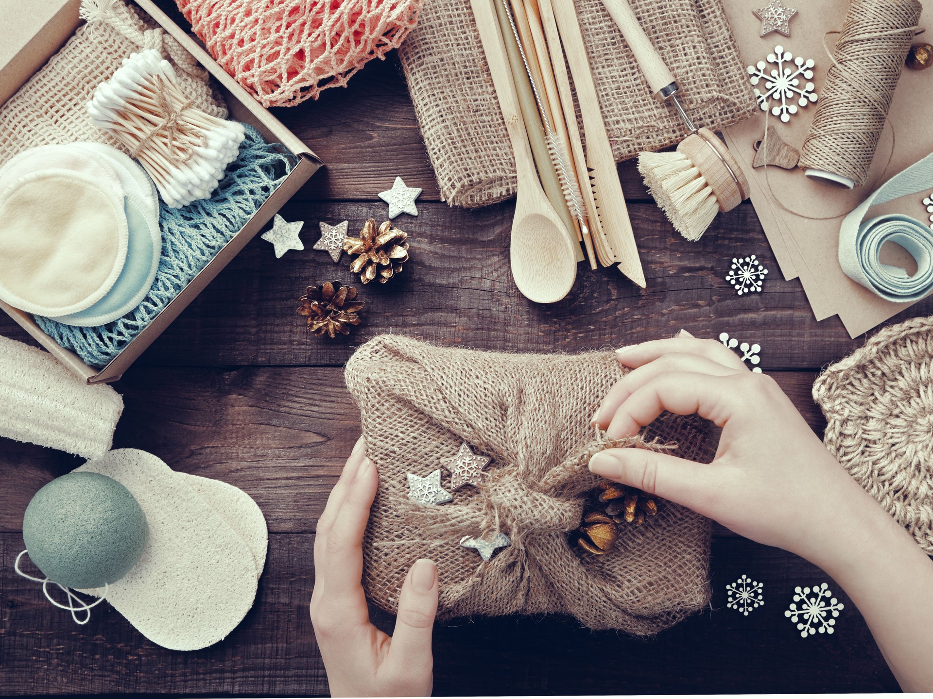 Null Verschwenden Weihnachten. Weibliche Hände packen Geschenk in Sackleinen gewickelt. Umweltfreundliche Produkte auf dem Tisch
